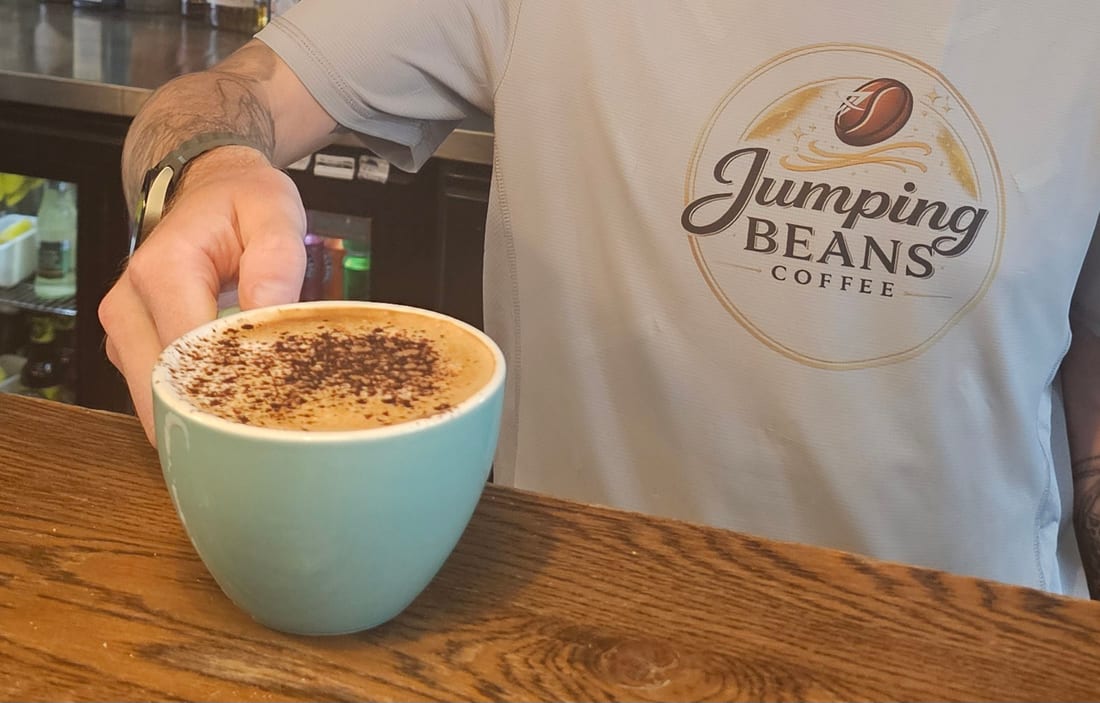 A Jumping Beans barista serving a fresh cappuccino